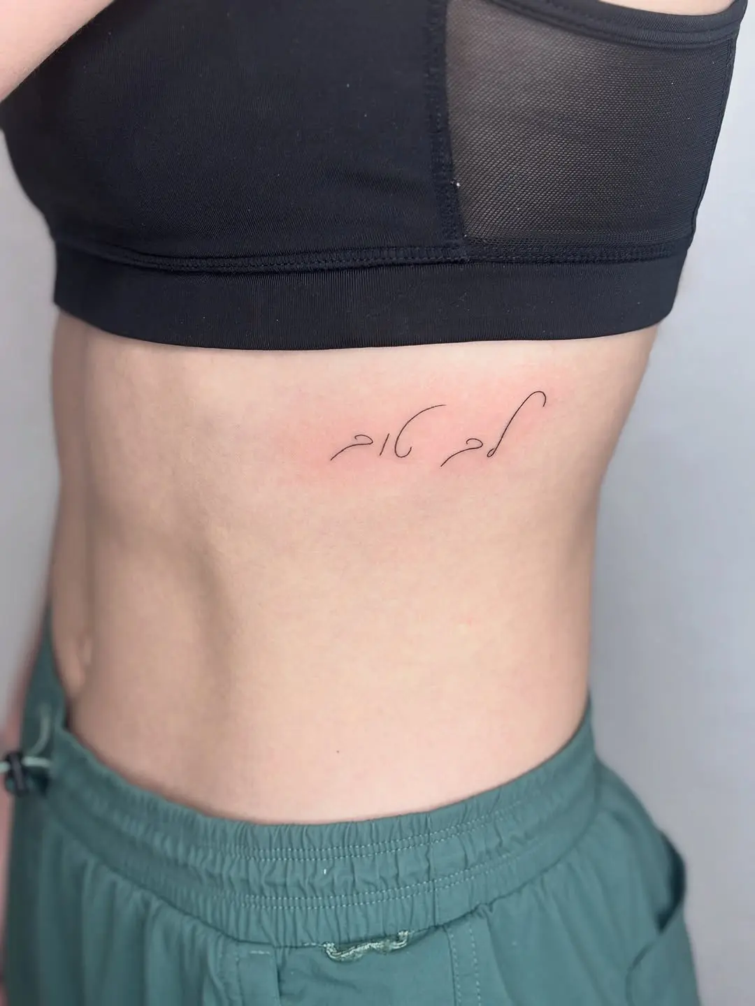 Elegant Hebrew Script Tattoo on Rib