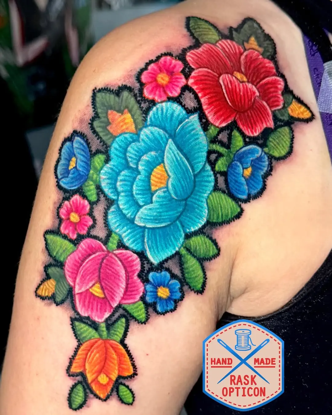 Vibrant floral embroidery tattoo on shoulder