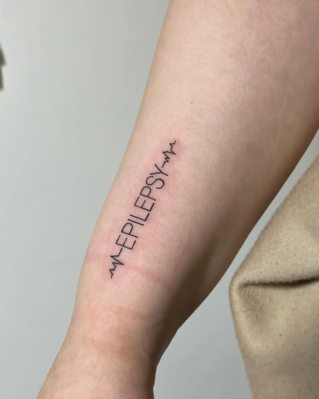 Minimalist epilepsy tattoo on the arm