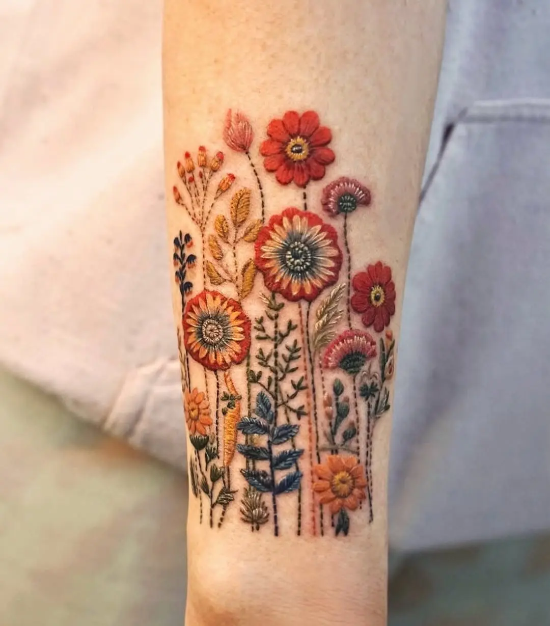 Vibrant floral embroidery tattoo on the arm