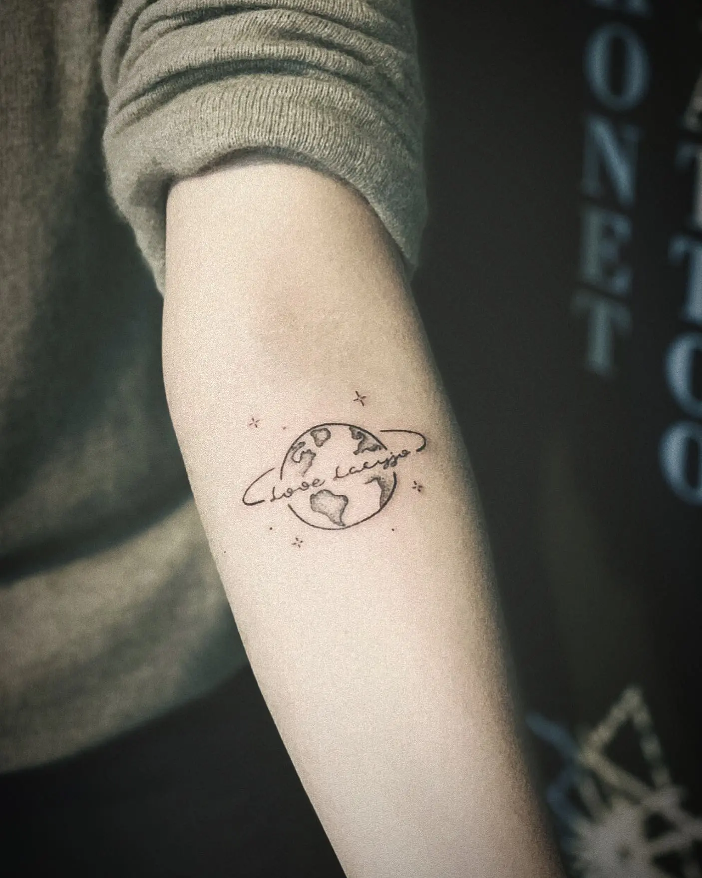 Minimalist globe tattoo with heart accents