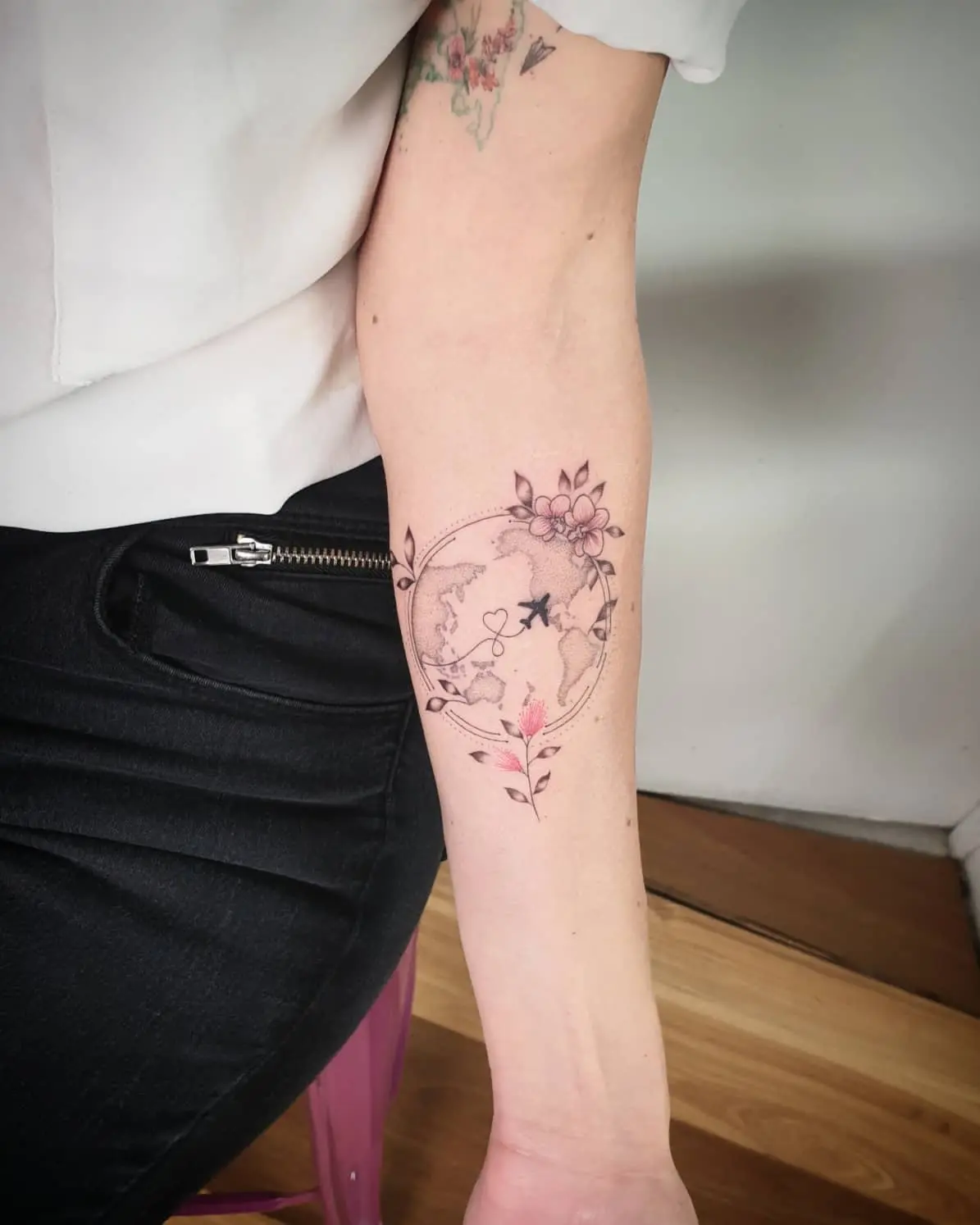 Delicate floral globe tattoo with travel vibes