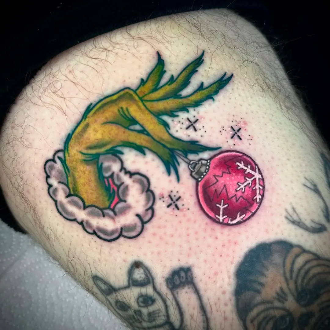Unique Grinch hand tattoo with Christmas ornament
