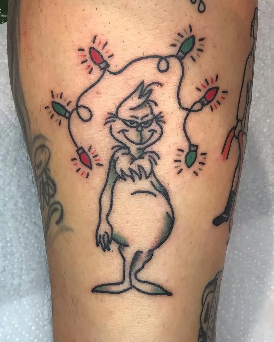 Whimsical Grinch Tattoo with Christmas Lights