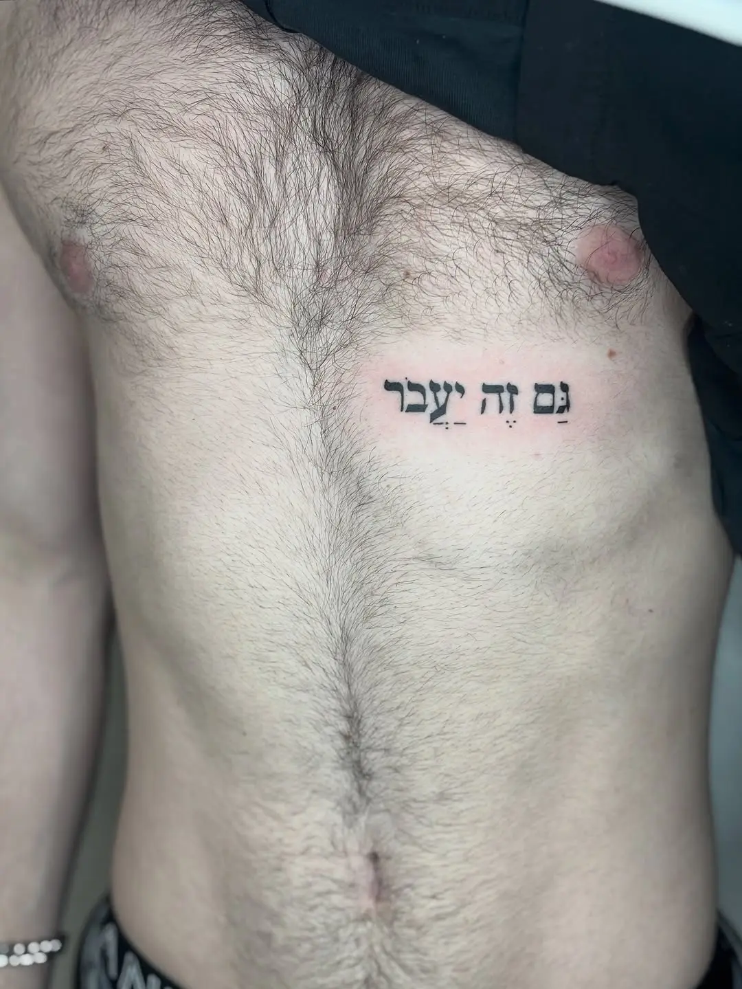 Expressive Hebrew script tattoo on the chest