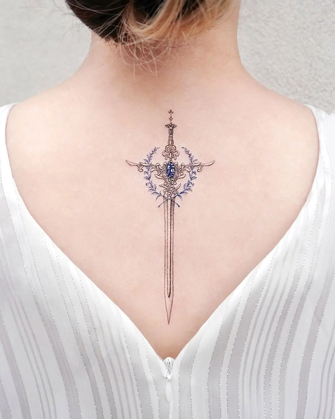 Elegant tattoo featuring laurel and sword design