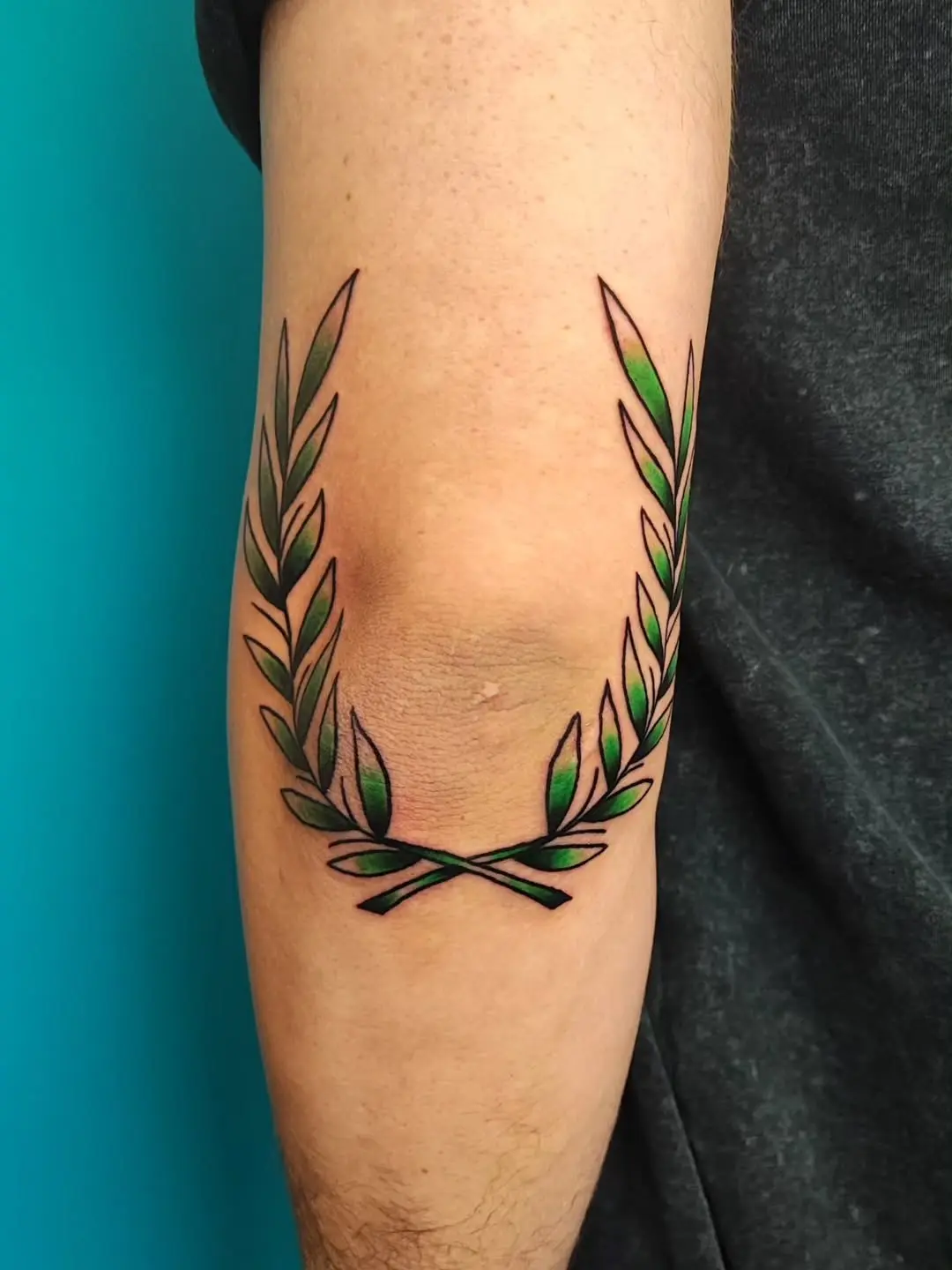Elegant laurel wreath tattoo encircles the elbow