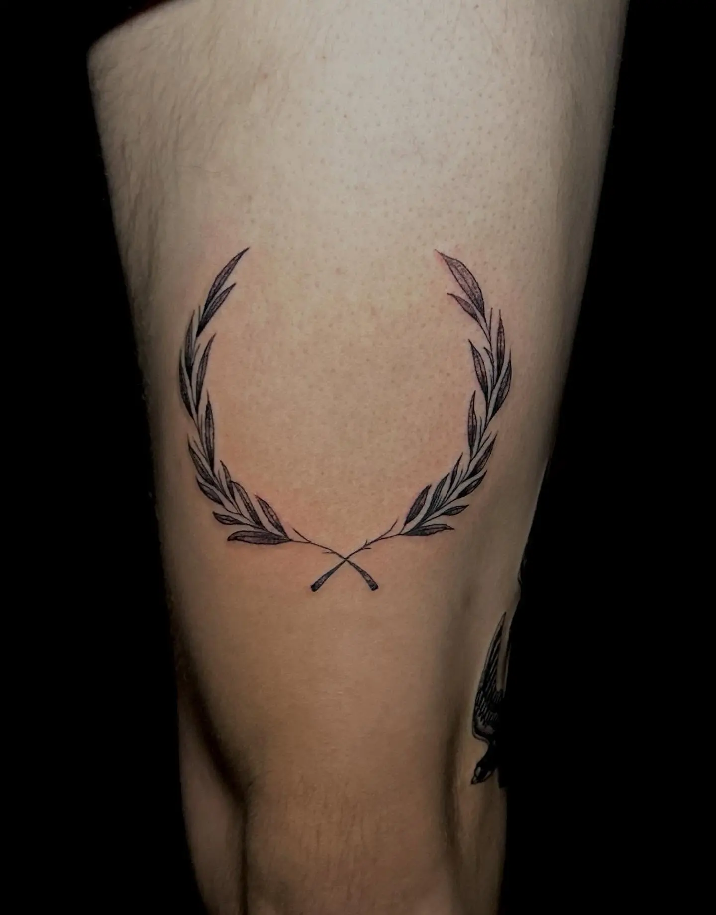 Elegant laurel wreath tattoo with crossed elements