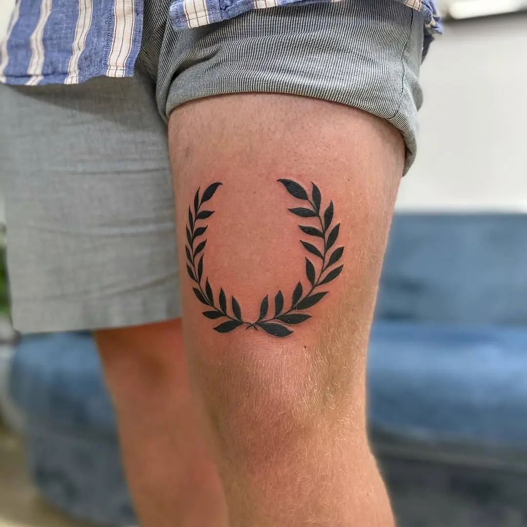 Bold and stylish laurel wreath thigh tattoo