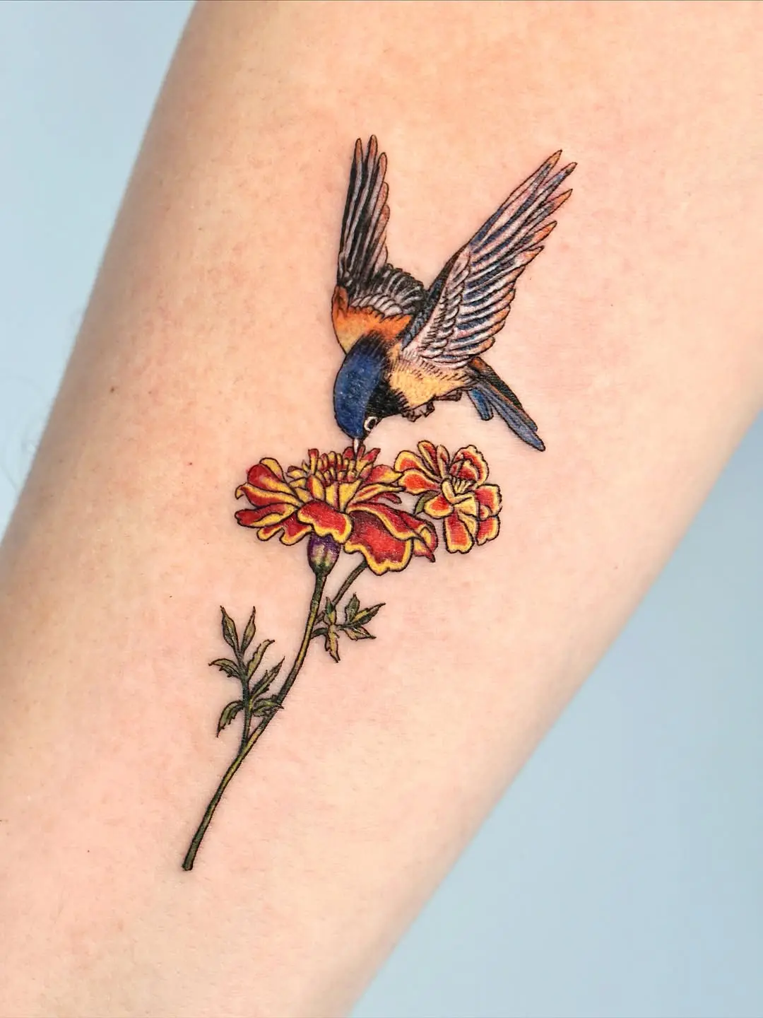 Charming marigold tattoo with vibrant bird detail
