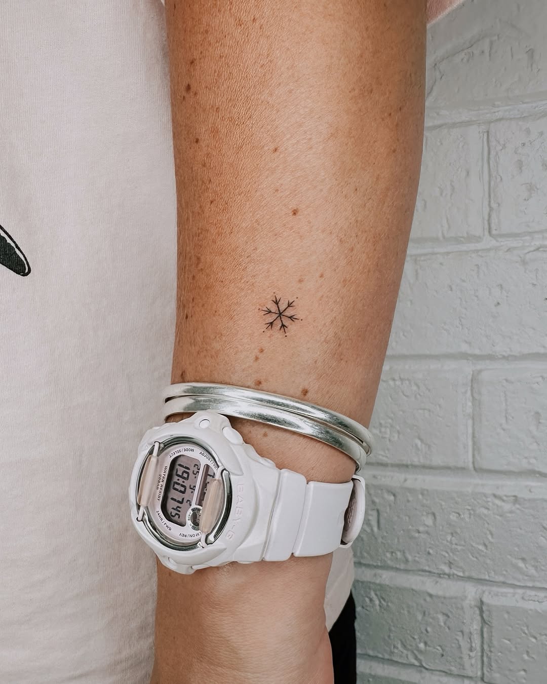 Delicate snowflake tattoo on wrist with accessories
