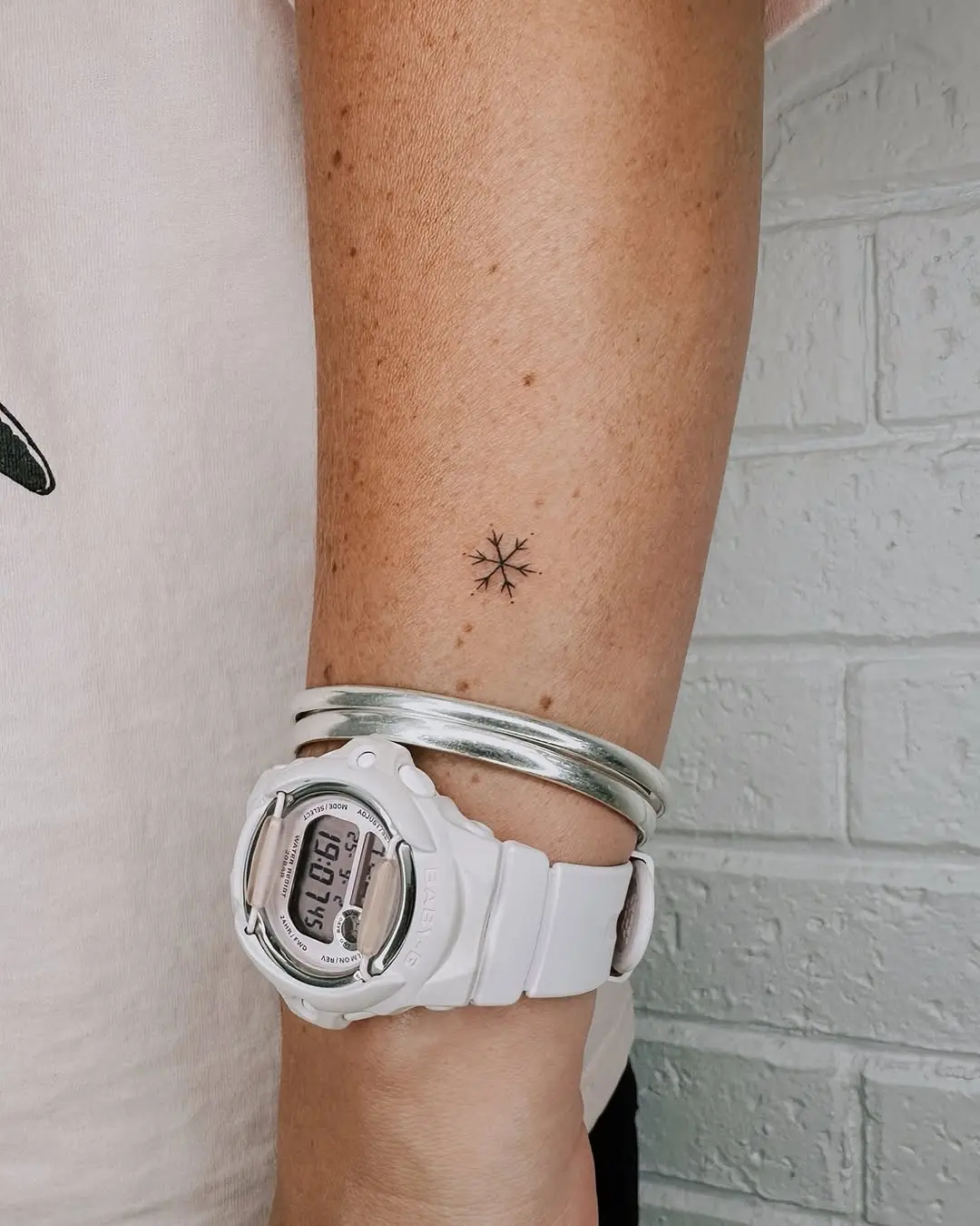 Delicate snowflake tattoo on wrist with accessories