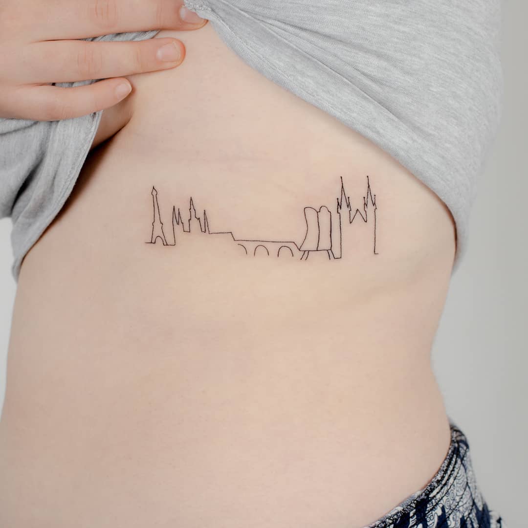 Stylish minimalist skyline tattoo on rib cage