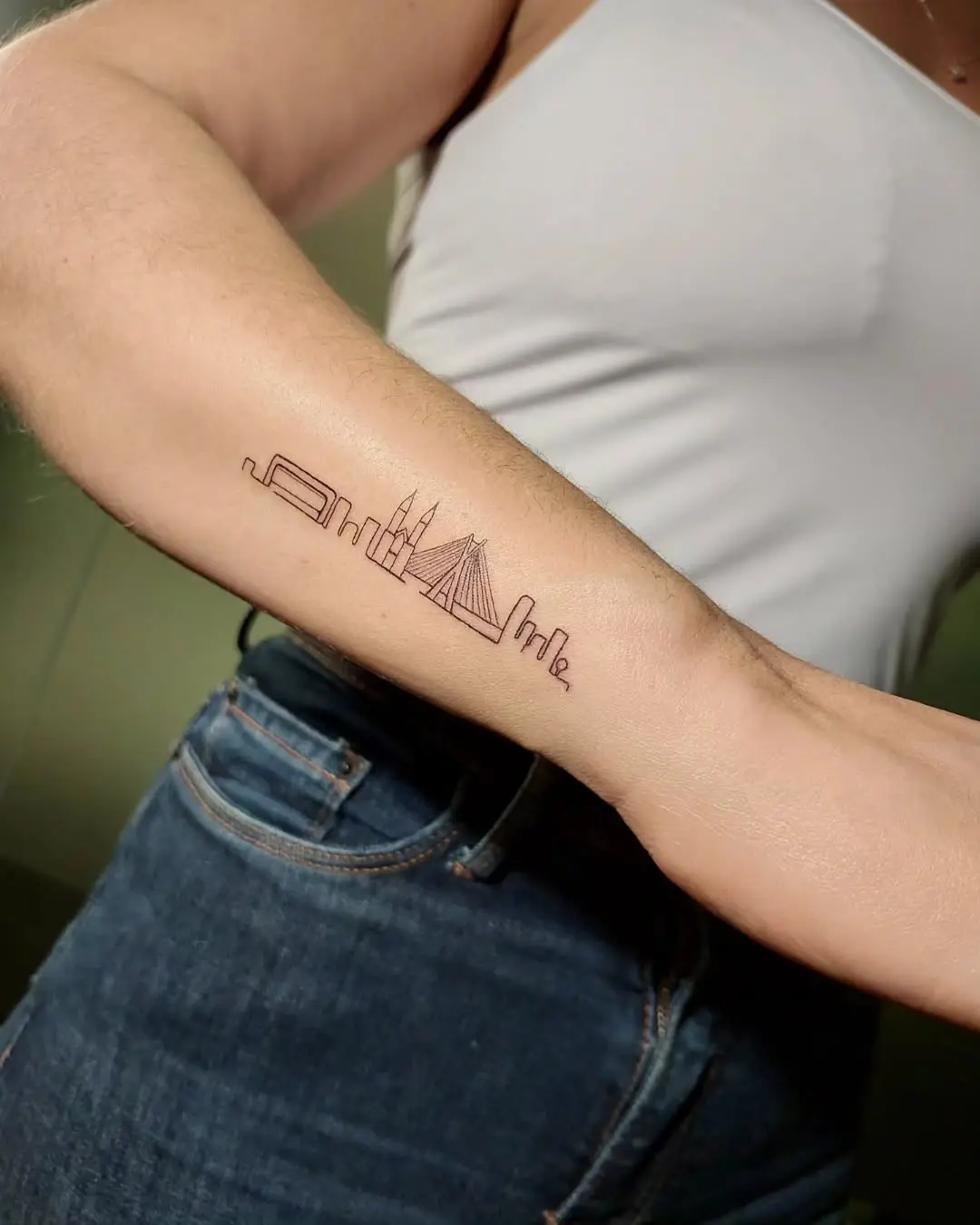 Minimalist skyline tattoo on a forearm