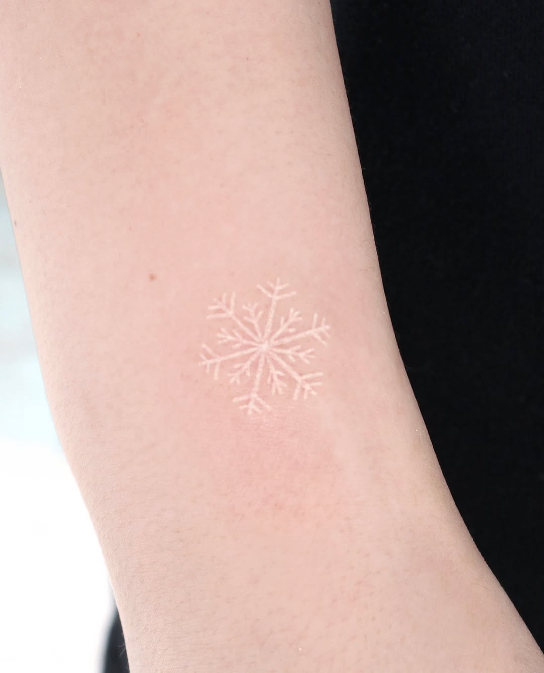 Delicate snowflake tattoo on bare skin