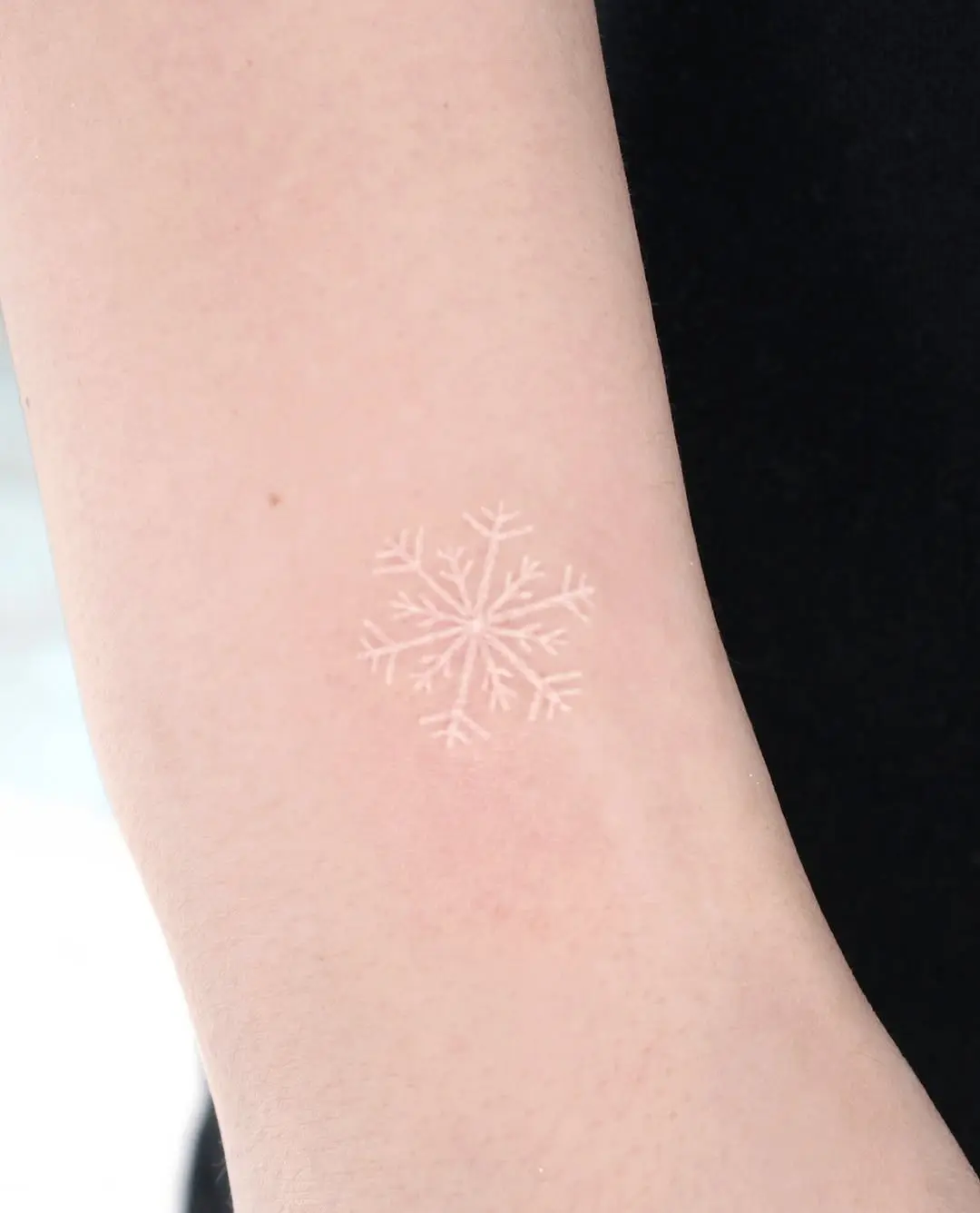 Delicate snowflake tattoo on bare skin