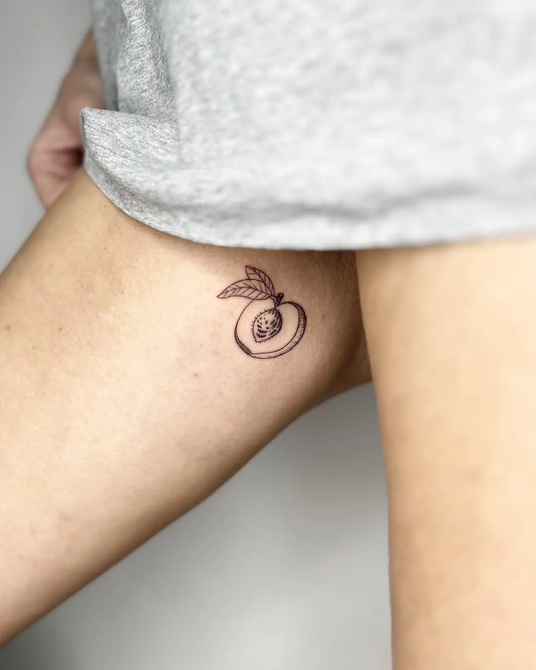 Chic and minimalist peach thigh tattoo design