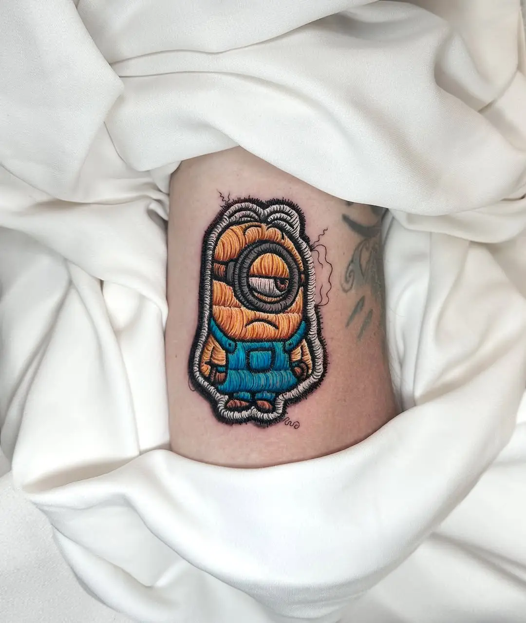 Whimsical minion-inspired embroidery tattoo design