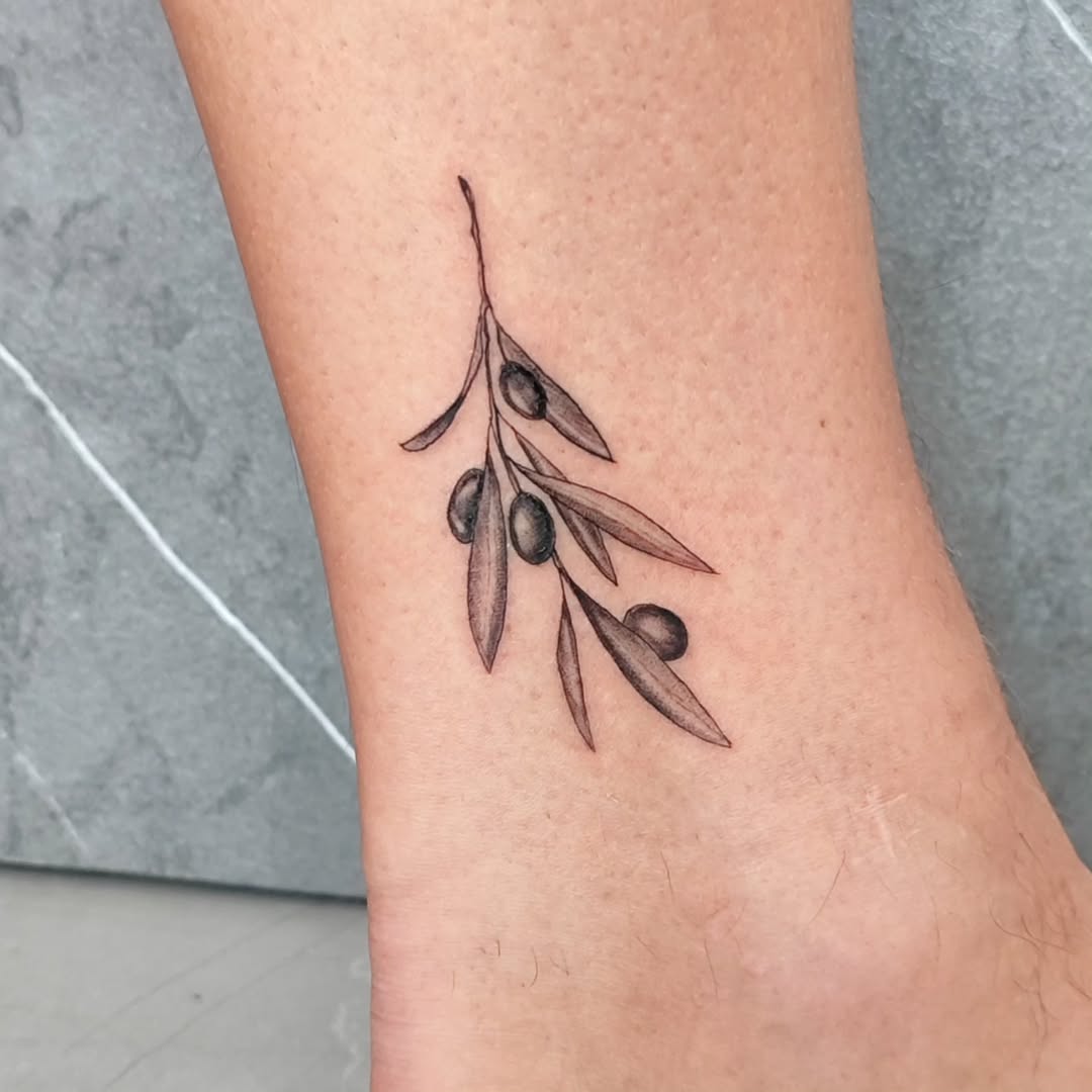 Delicate olive branch tattoo on ankle design.