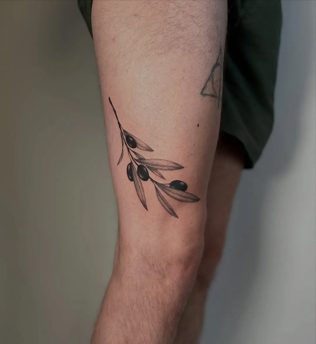 Elegant olive branch tattoo on thigh