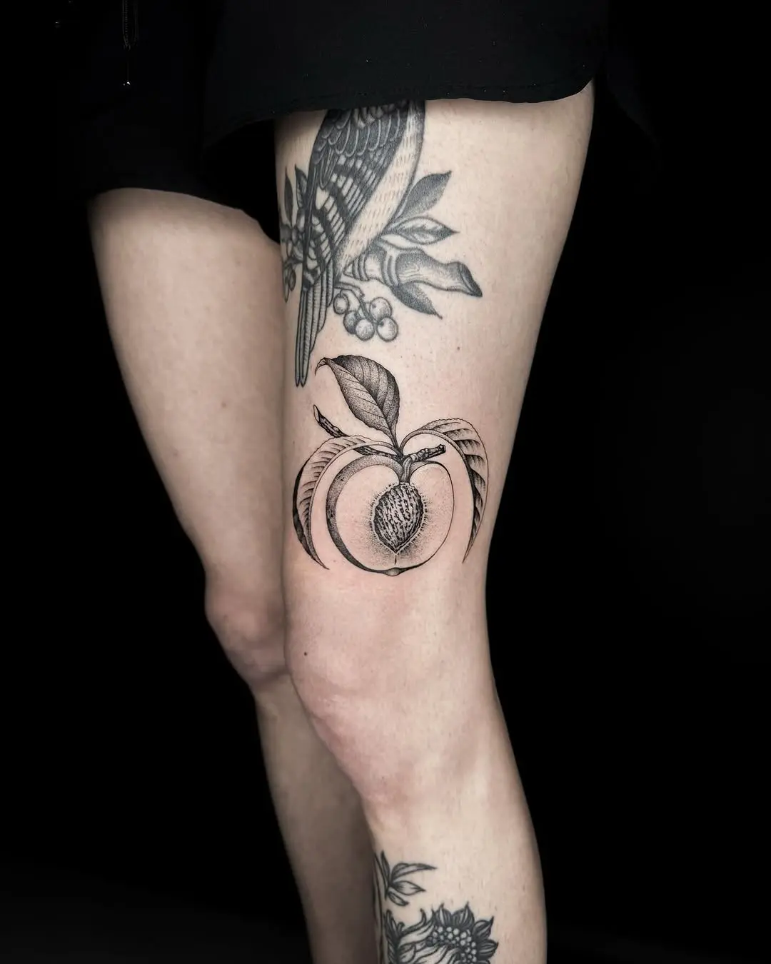 Elegant peach tattoo showcases bold blackwork artistry