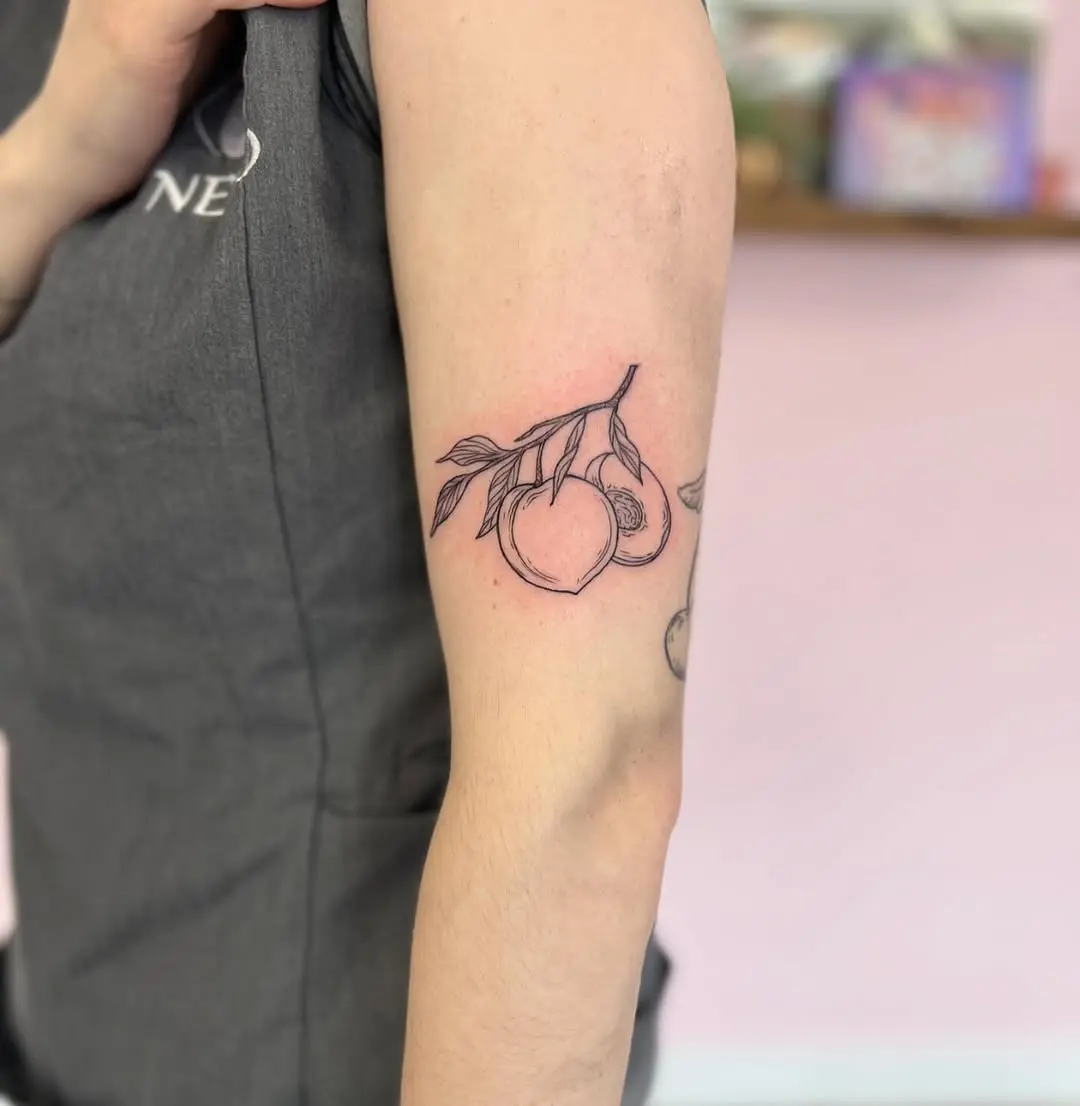 Charming minimalistic peach tattoo on arm