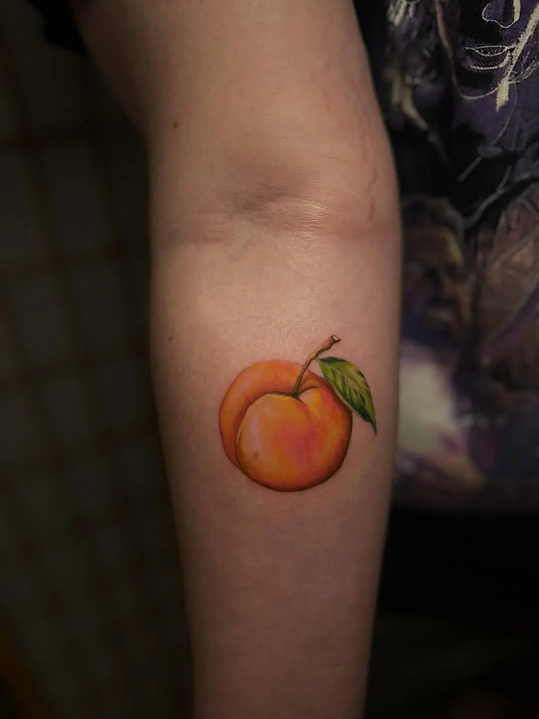 Vibrant peach tattoo on the inner arm