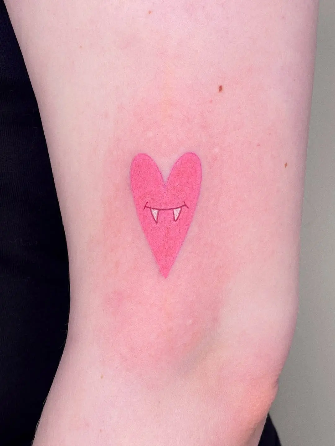 Charming pink heart with playful vampire fangs