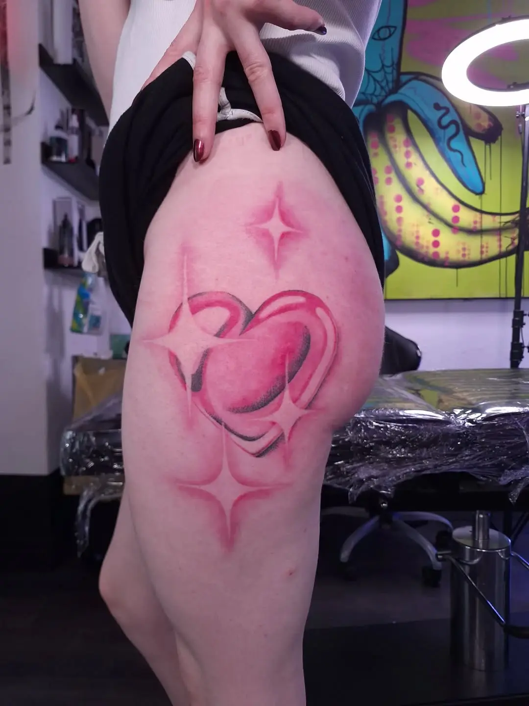 Vibrant pink heart tattoo with star accents