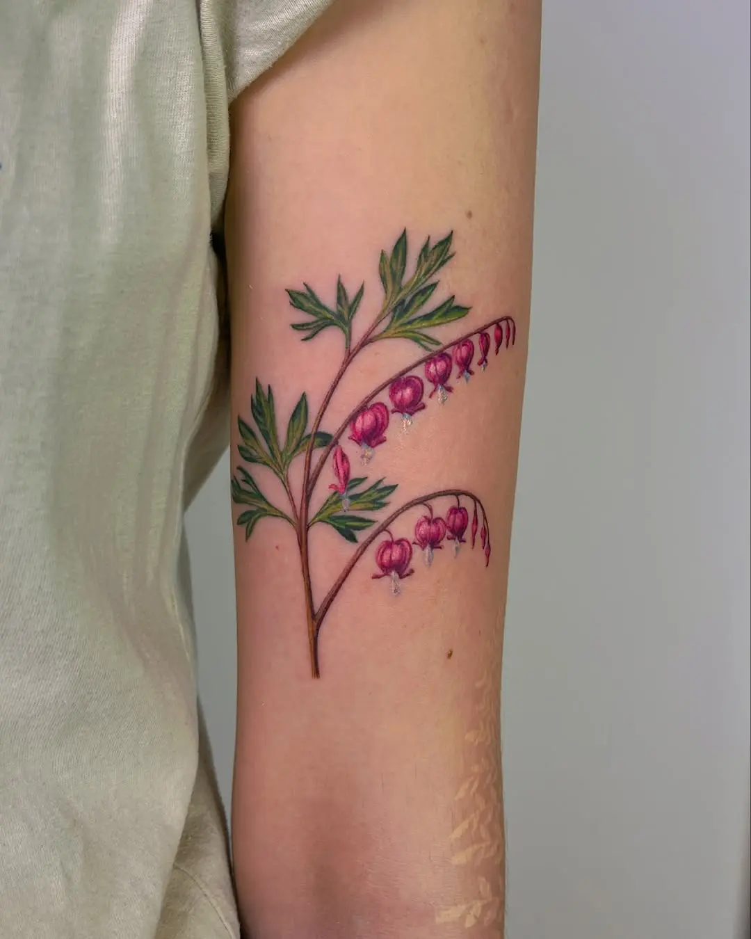 Delicate pink floral tattoo on the arm