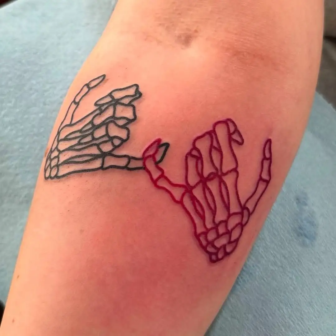 Skeletal hands forming a pinky promise tattoo