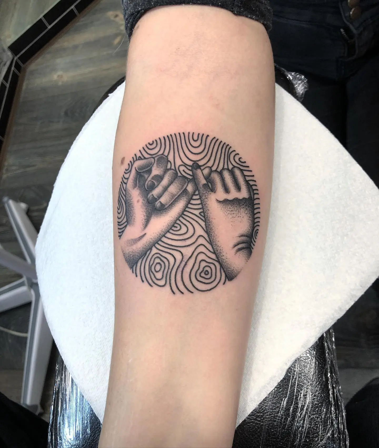 Artistic pinky promise tattoo with circular pattern