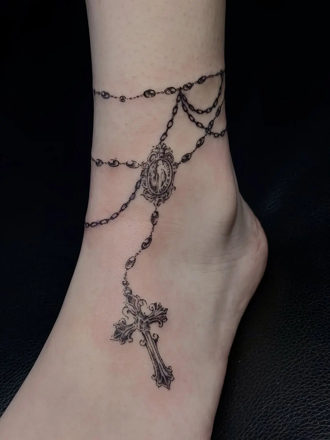 Elegant rosary tattoo wrapped around the ankle