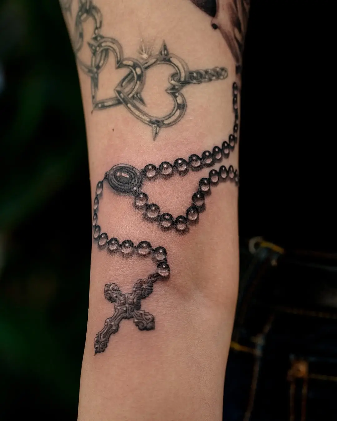 Intricate rosary tattoo with a bold black cross