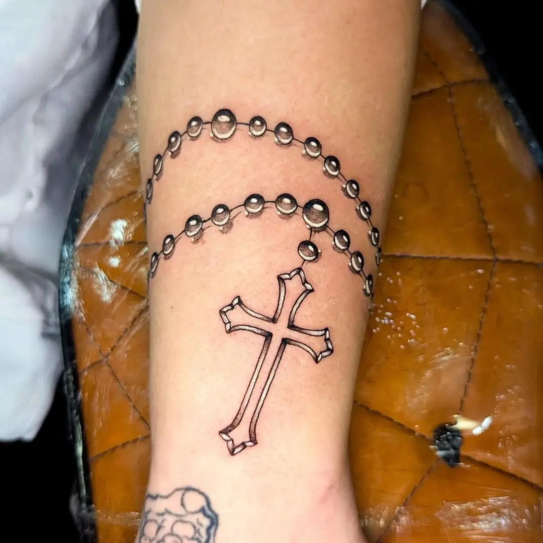 Elegant black ink rosary tattoo on arm