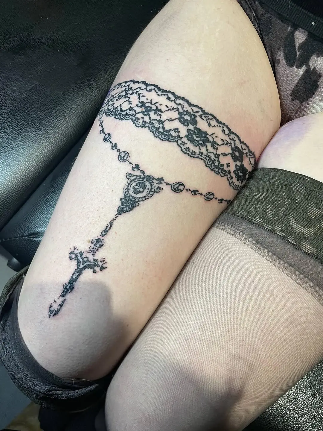 Elegant lace rosary tattoo on thigh