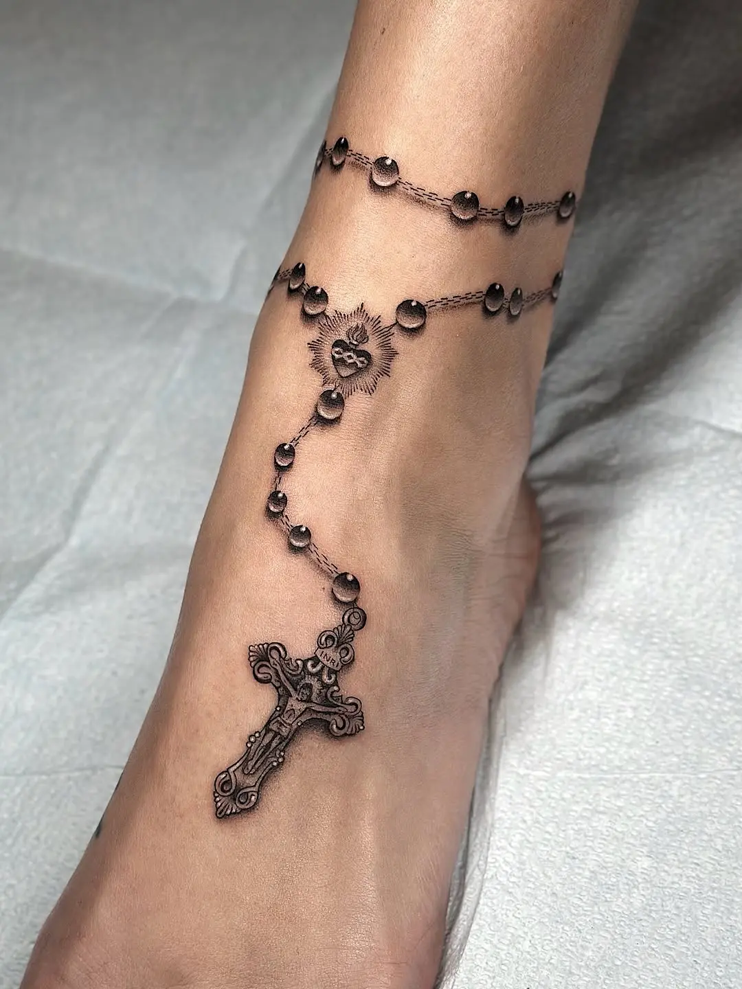 Stylish ankle rosary tattoo with sacred elements