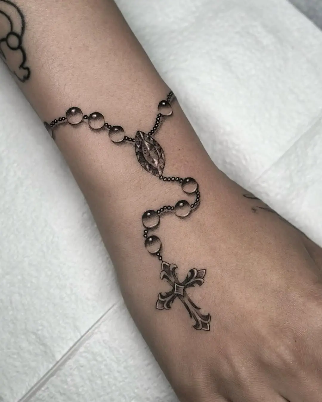 Elegant wrist rosary tattoo design with cross
