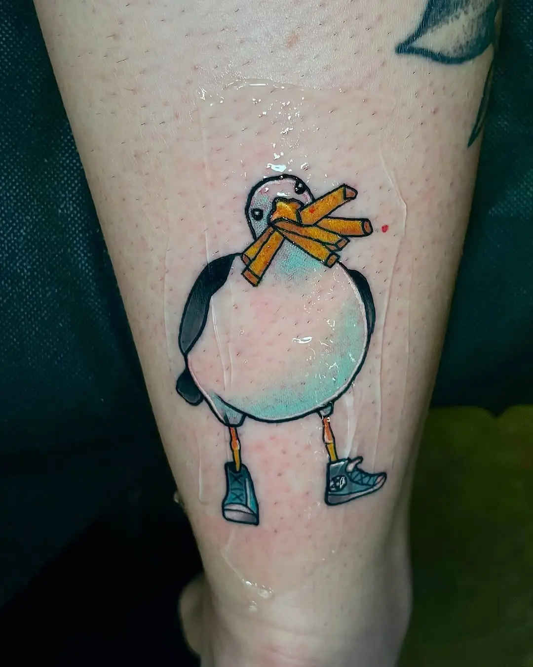 Whimsical seagull with fries and shoes tattoo