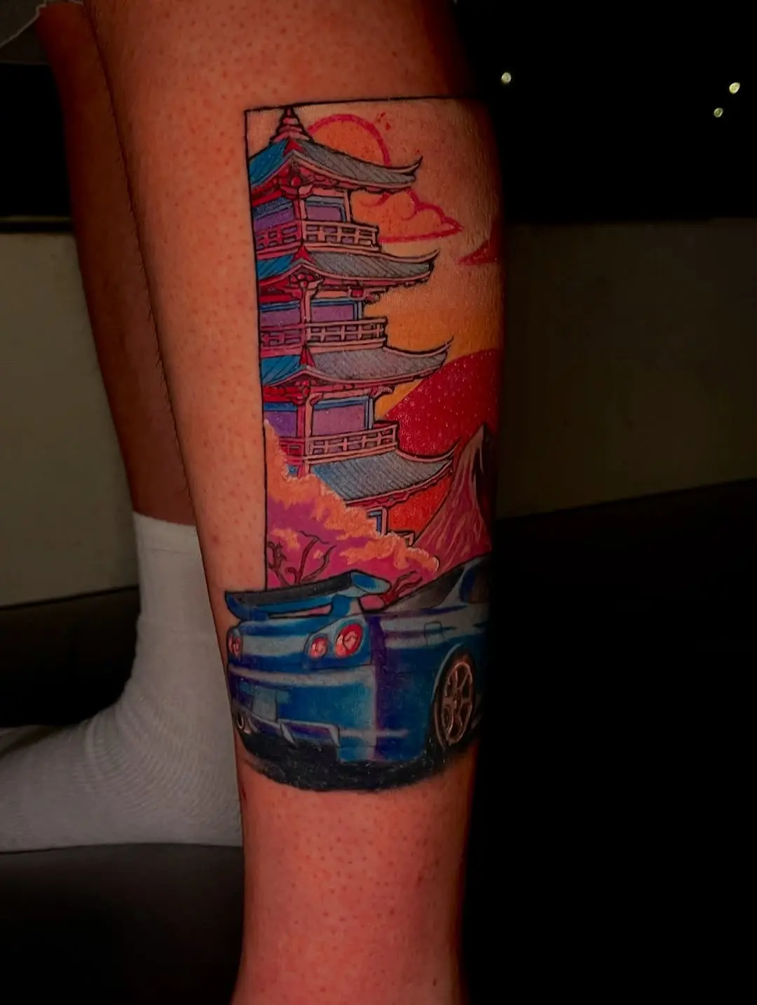 Vibrant skyline tattoo with a car focal point.