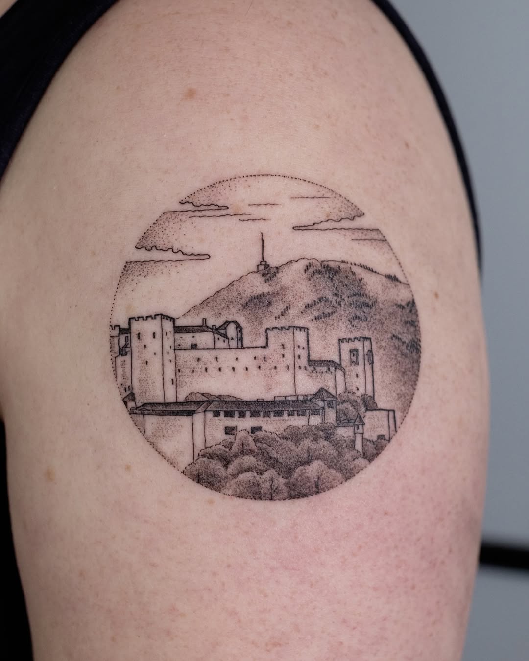 Circular skyline tattoo featuring a mountain view.