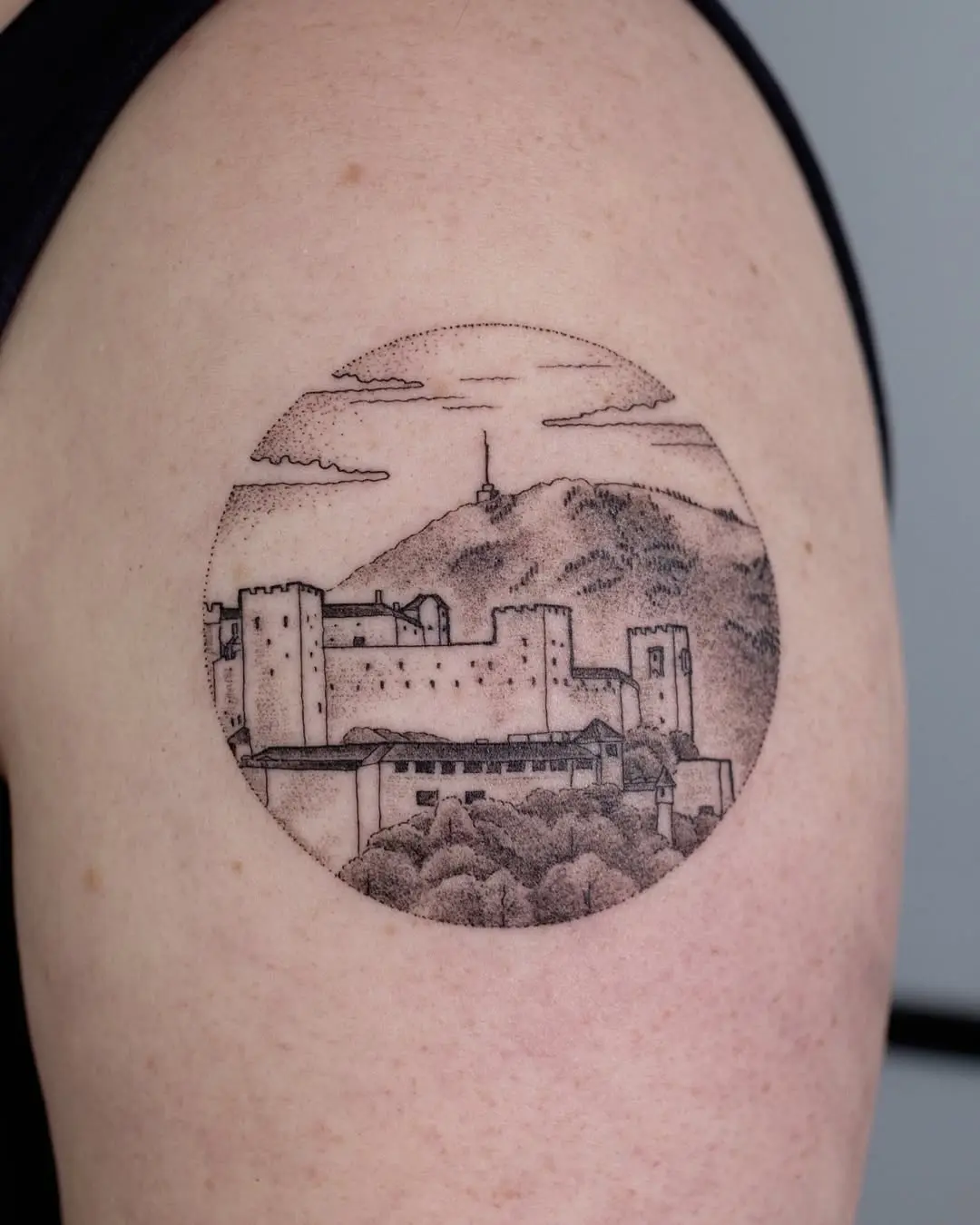 Circular skyline tattoo featuring a mountain view.