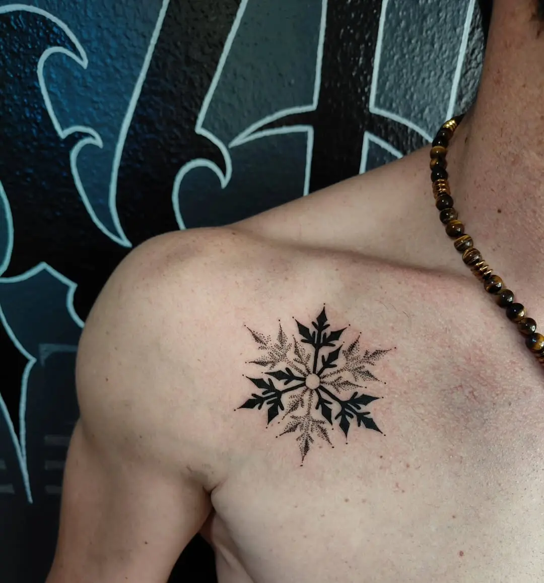 Intricate black ink snowflake tattoo on shoulder
