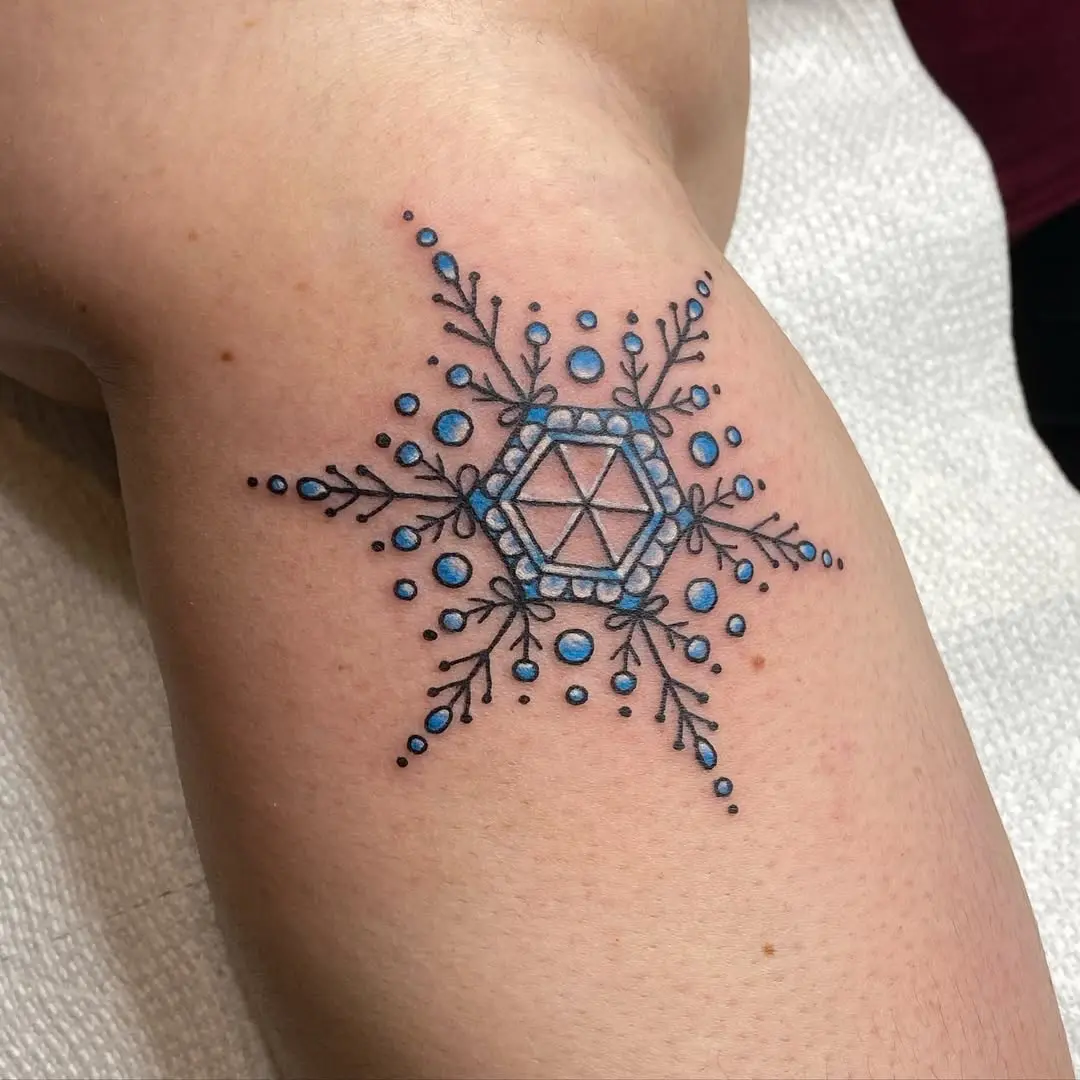 Intricate blue snowflake tattoo design on arm