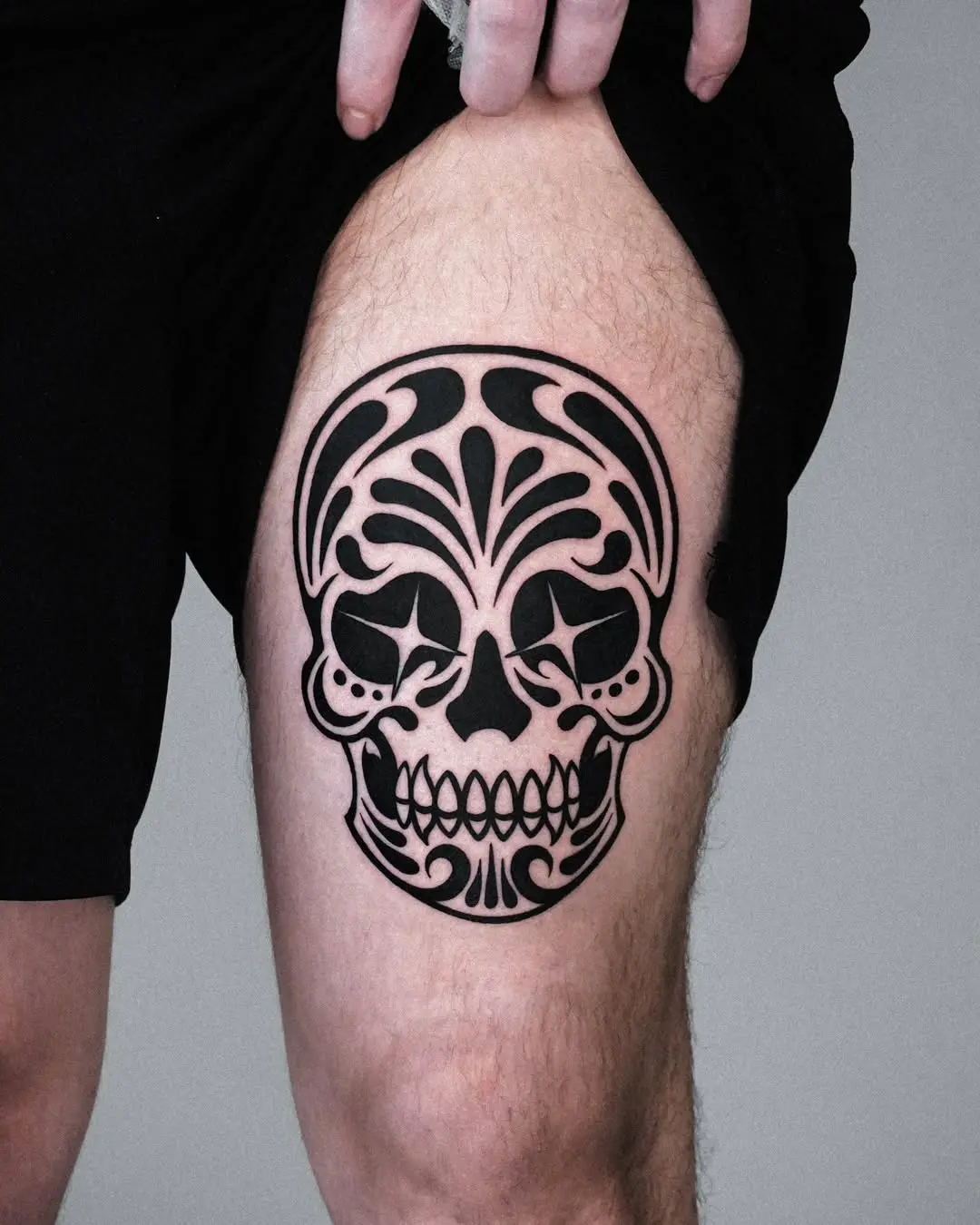 Striking black sugar skull tattoo on thigh