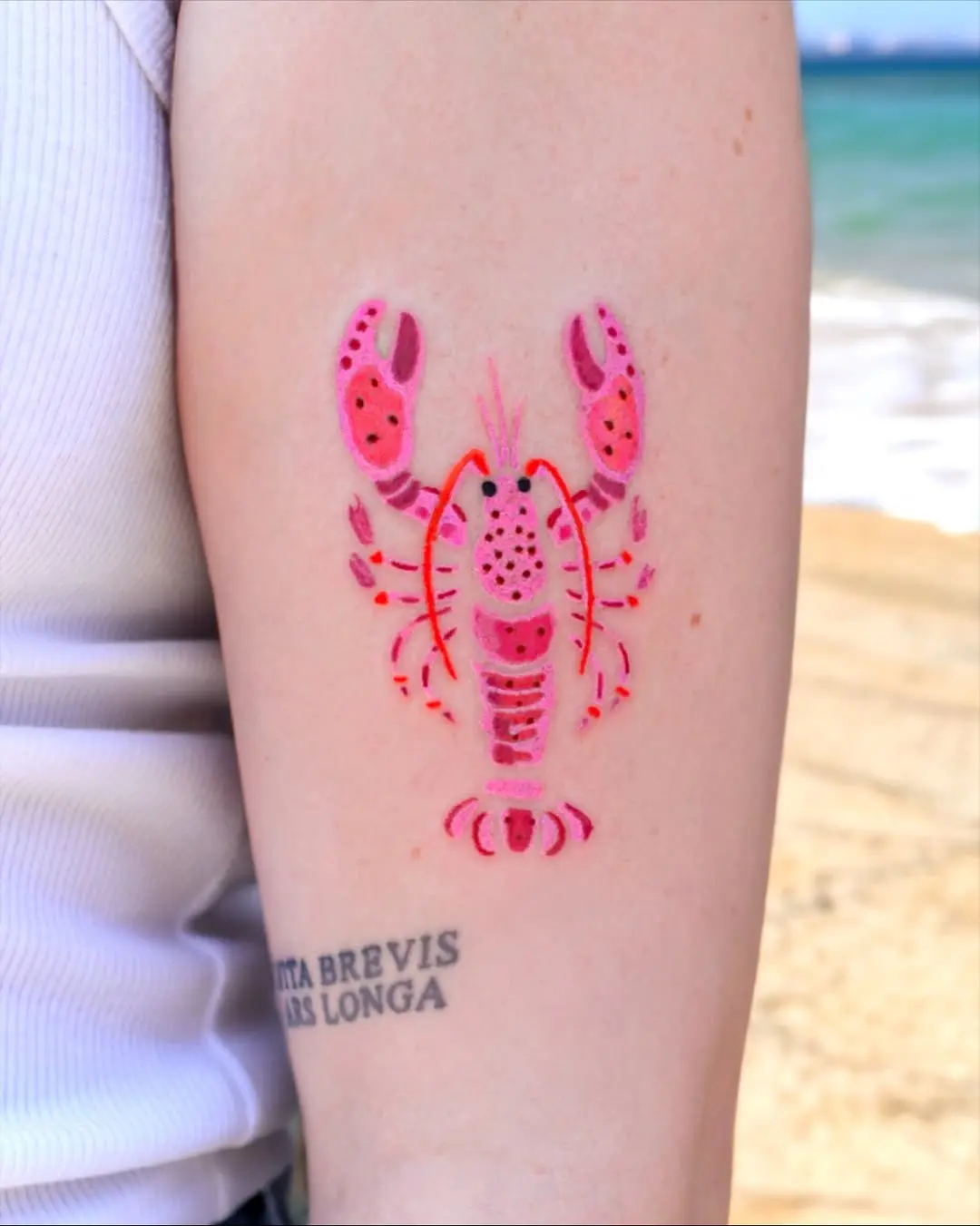 Vibrant lobster tattoo with beach backdrop
