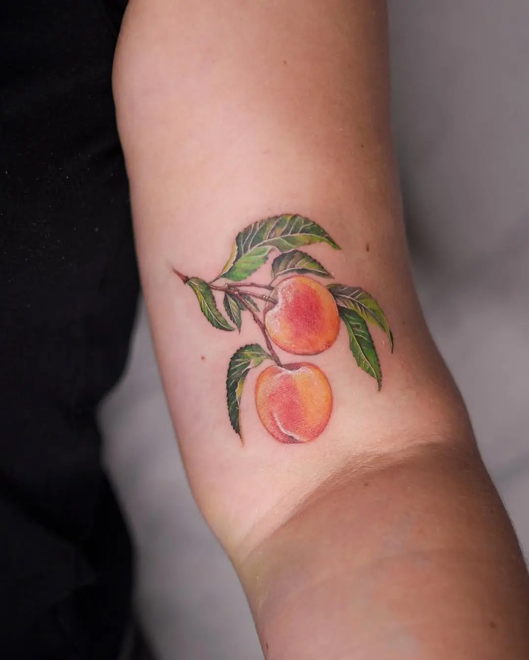 Colorful peach tattoo with lush green leaves