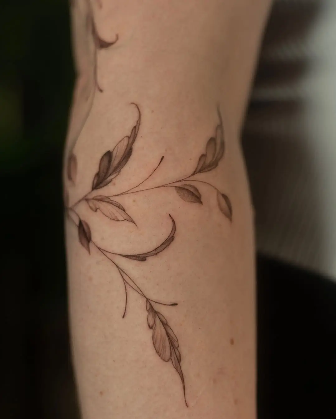 Elegant vine tattoo wrapping around the elbow