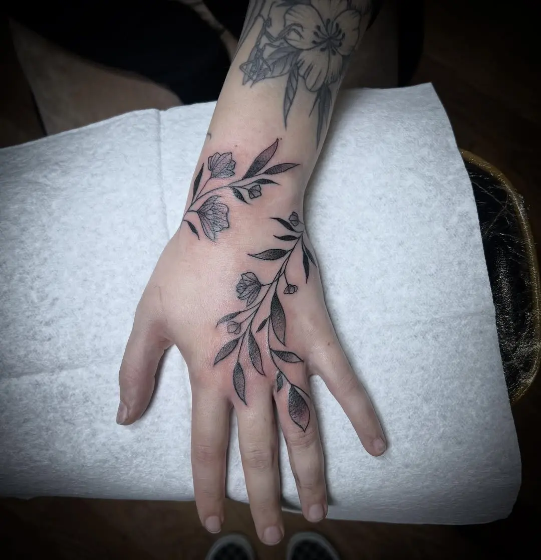 Elegant vine tattoo wraps around the hand