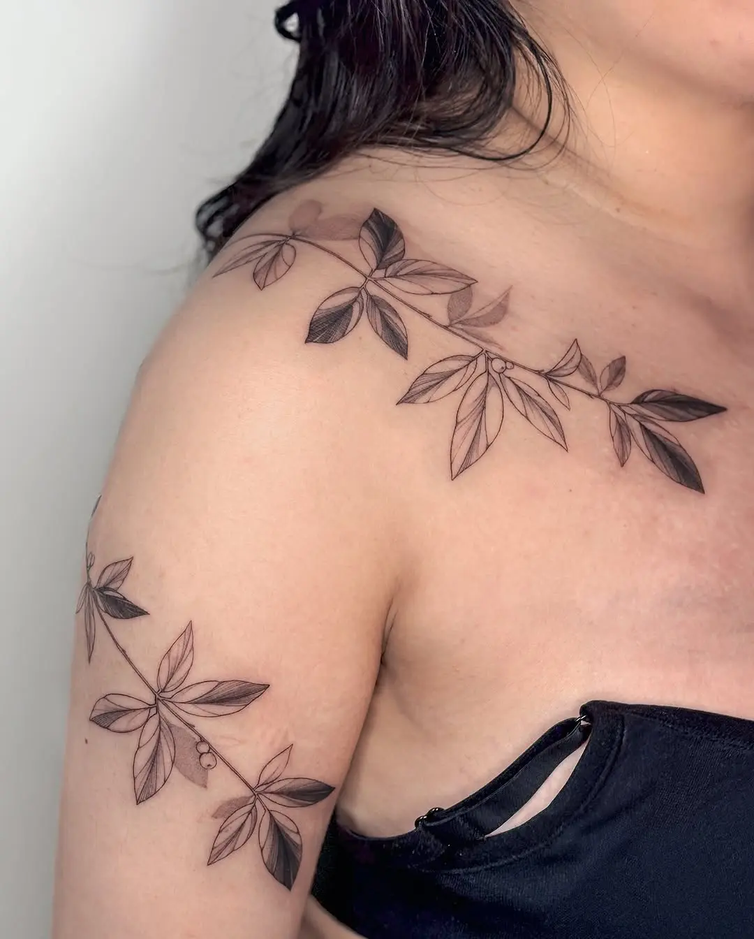 Elegant vine tattoo wraps around the shoulder